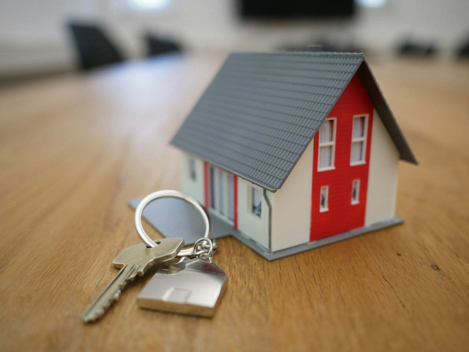 A set of house keys beside a small model home